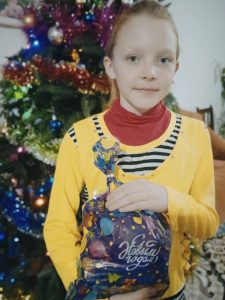 Fröhliches Mädchen mit Geschenk für den Weihnachtsbaum