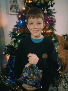 Glücklicher Junge mit Geschenk für den Weihnachtsbaum